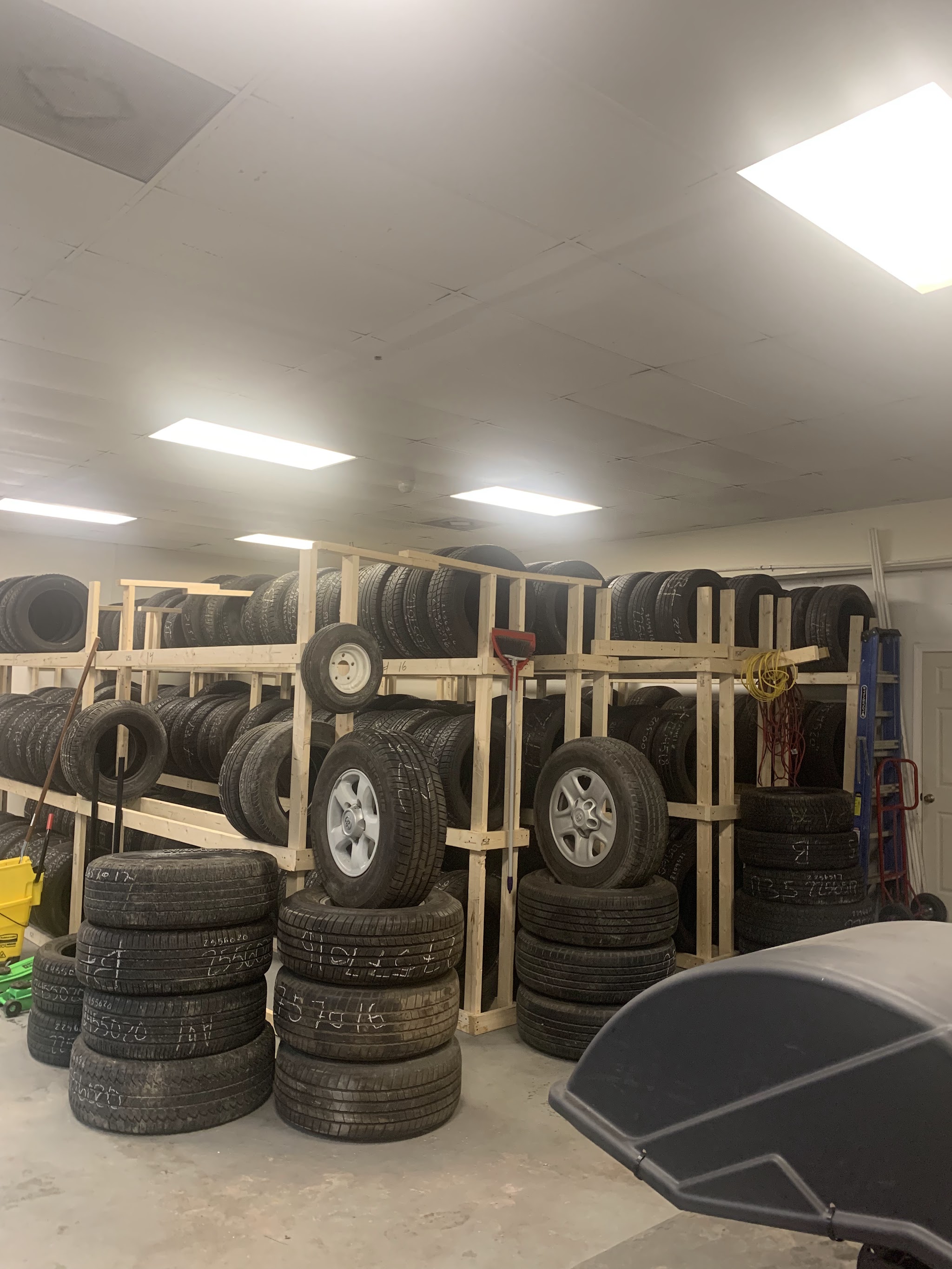 Back room with wooden racks full of used tires and spare wheels